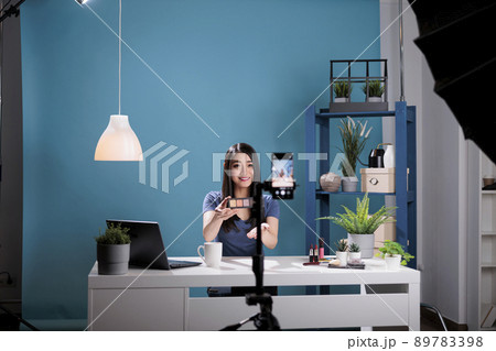Behind the scene of influencer holding make up palette doing cosmetic review while recording beauty podcast in studio. Content creator person advertising cosmetology product during live tutorial 89783398