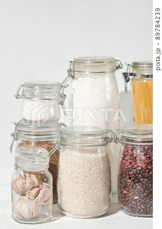eco friendly kitchen storage. keeping food fresh, glass jars full of grains , pasta and flour. transparent containers for pantry. vertical shot eco friendly kitchen storage. keeping food fresh, glass jars full of grains , pasta and flour. transparent containers for pantry. vertical shot 89784239