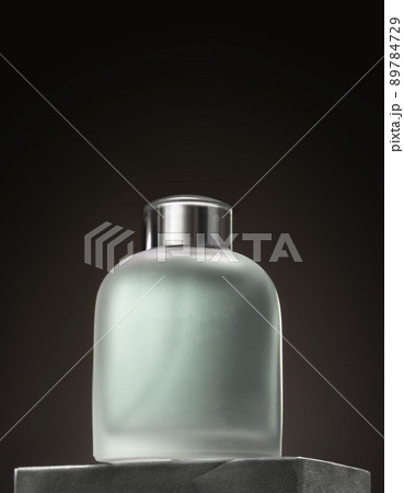 Glass perfume bottle on grey podium. Minimal mockup style, soft focus 89784729