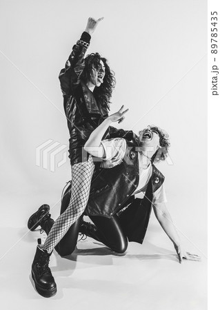 Studio shot of excited, astonished young boy and girl with bright makeup wearing black leather outfits moving on white background. Music, youth 89785435