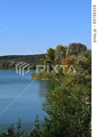Forest lake in the autumn afternoon. Calm water with reflection of trees. 89786916