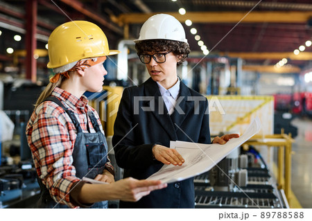Confident master in hardhat and black formalwear presenting sketch to engineer 89788588