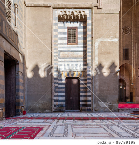 Wall with striped black and white marble decorations, wooden grunge door and window, Sultan Hassan mosque, Cairo, Egypt 89789198