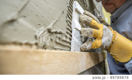 Closeup of workman carefully positioning an ornamental tile in a glue 89789876