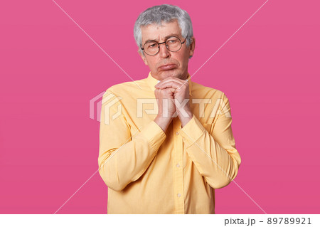 Close up shot of elderly man with wrinkles on face, pouty lips, looks offended, shows resentful facial expressiondiscontent with something, dressed in shirt and bow tie. Emotions and feelings concept Close up shot of elderly man with wrinkles on face, pouty lips, looks offended, shows resentful facial expressiondiscontent with something, dressed in shirt and bow tie. Emotions and feelings concept 89789921