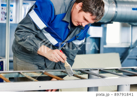 Painter of 30-40 years of Caucasian appearance paints metal structure in production hall with paint 89791841