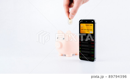 Internet based banking. Mobile phone with internet online bank app. Piggy bank with hundred dollar bill on white background. Online wallet save money. 89794396