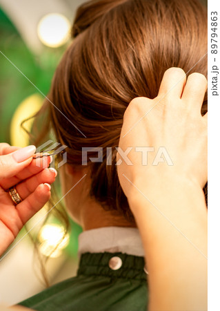 Hairstyling bride. A female hairdresser makes styling hair for the beautiful young caucasian woman in a beauty salon 89794863
