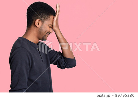 Sideways man realizes his mistake, keeps hand on forehead, dressed in casual clothes, regrets about something, dressed in casual jumper, isolated over pink wall with blank space for your text 89795230