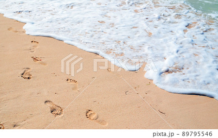 Bare footprints and shore foam are over wet beach sand, summer vacation Bare footprints and shore foam are over wet beach sand, summer vacation 89795546
