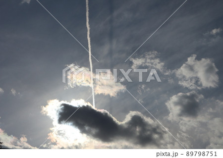 太陽の光りでふちが白く輝く灰色雲と白い飛行機雲と色々な色や形の雲と青空のある不思議な空の風景 太陽の光りでふちが白く輝く灰色雲と白い飛行機雲と色々な色や形の雲と青空のある不思議な空の風景 89798751