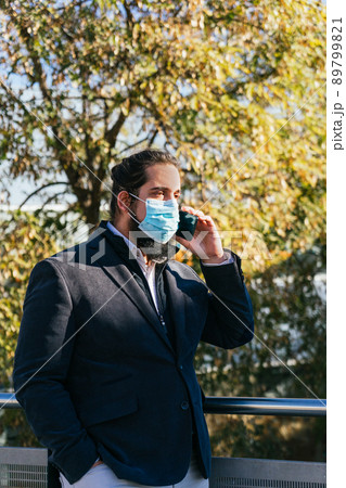 Young business man talking mobile with face mask 89799821