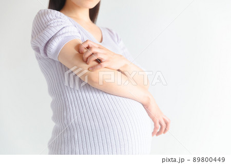 二の腕を掻く妊婦　妊娠掻痒疹 89800449