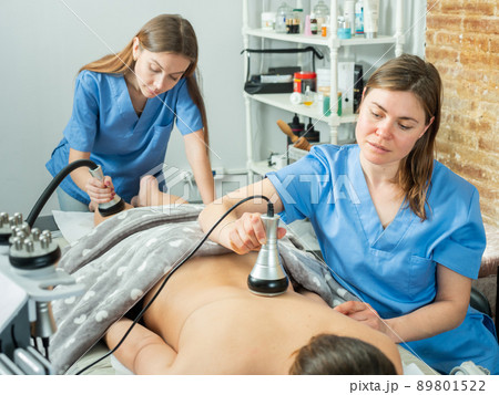 Women doctors performing hardware body procedure to female patient Women doctors performing hardware body procedure to female patient 89801522