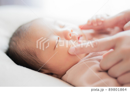 ほっぺをつつく指を握る赤ちゃん 把握反射 コミュニケーションの写真素材