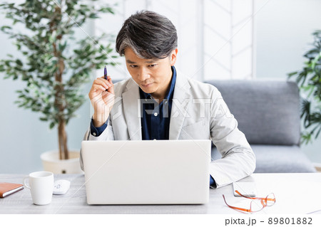 ソファのある明るい部屋でデスクワークをしているビジネスマン 89801882