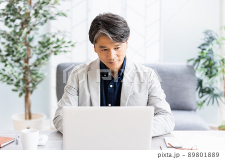 ソファのある明るい部屋でデスクワークをしているビジネスマン ソファのある明るい部屋でデスクワークをしているビジネスマン 89801889