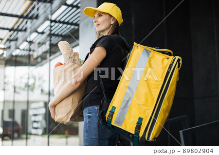 Smiling delivery woman holding paper bag with organic vegetables. 89802904