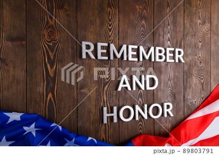 words remember and honor laid with silver metal letters on wooden background with USA flag underneath 89803791