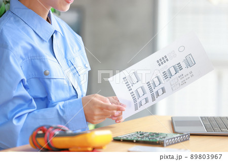 図面を持ち基板を指さしチェックするエンジニア女性の手元1 89803967