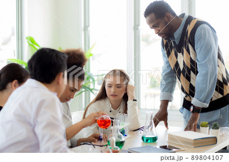 Young teacher teaching group student about science and test chemical for liquid in the lab of school Young teacher teaching group student about science and test chemical for liquid in the lab of school 89804107