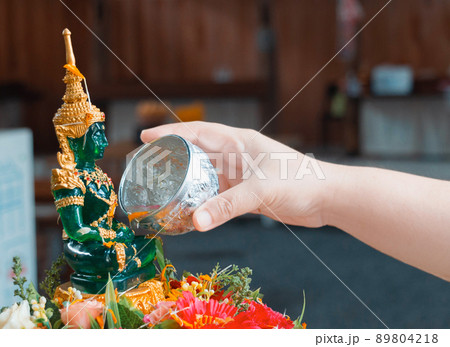 woman's hand pouring water to emerald buddha image woman's hand pouring water to emerald buddha image 89804218