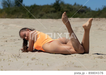 Fit woman in swimsuit sunbathing on sandy beach Fit woman in swimsuit sunbathing on sandy beach 89804376