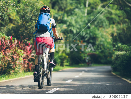 Woman cycling on tropical park trail in summer 89805137