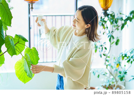 部屋の観葉植物に水をあげる女性 部屋の観葉植物に水をあげる女性 89805158
