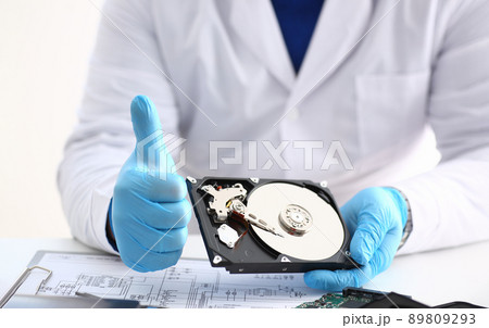 Man in uniform hold disassembled hard drive from computer, hdd and reader, show thumbs up 89809293