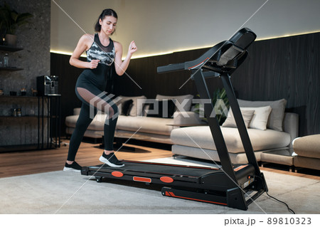 female feet running on treadmill in sport shoes, close up 89810323