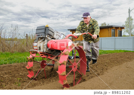 The farmer cultivates the soil for planting potatoes. The farmer cultivates the soil for planting potatoes. 89811202