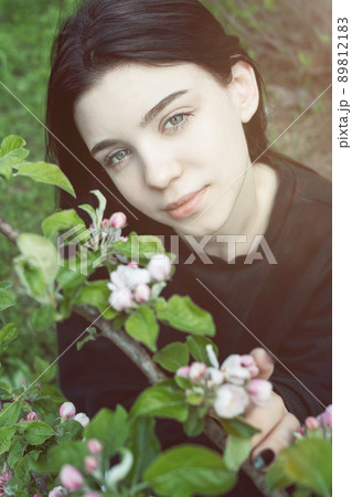 Pretty  teen girl are posing in garden near blossom apple tree with pink flowers. 89812183