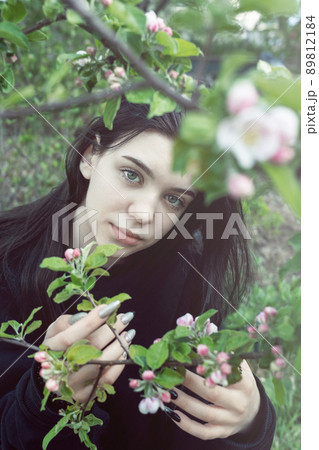 Pretty  teen girl are posing in garden near blossom apple tree with pink flowers. 89812184