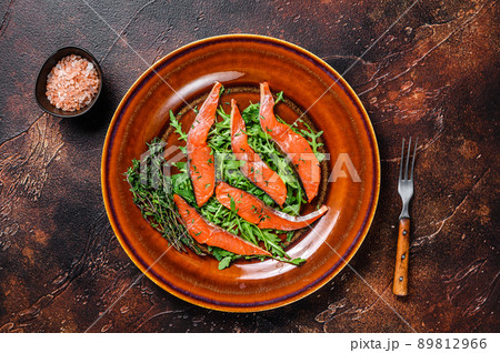 Salad with arugula and smoked salmon fillet slices. Dark background. Top view 89812966