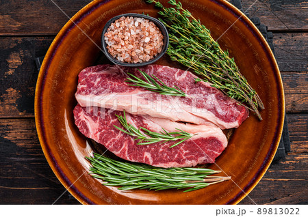 Two sliced Raw Striploin steaks or New York steaks, beef meat. Dark wooden background. Top view Two sliced Raw Striploin steaks or New York steaks, beef meat. Dark wooden background. Top view 89813022