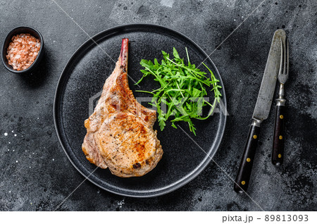 BBQ Grilled tomahawk pork chop meat steak on a marble board. Black background. Top view BBQ Grilled tomahawk pork chop meat steak on a marble board. Black background. Top view 89813093
