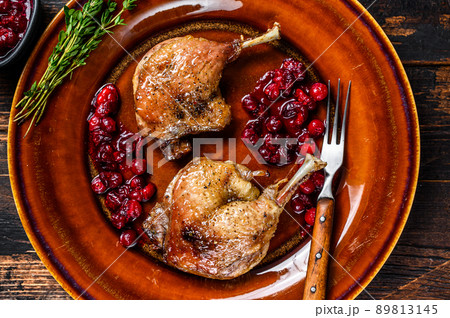 Roasted Christmas duck legs with cranberrie sauce. Dark wooden background. top view Roasted Christmas duck legs with cranberrie sauce. Dark wooden background. top view 89813145