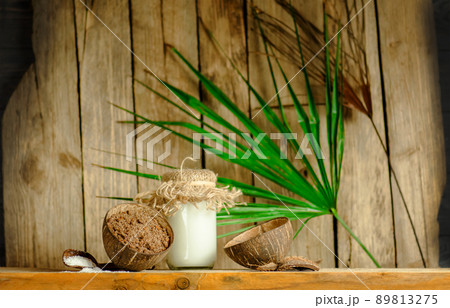 Coconut oil with fresh nut on old wooden table.  89813275