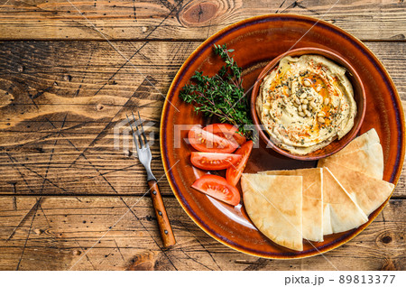 Fresh Hummus with pita bread, tomato and parsley on a rustic plate. wooden background. Top view. Copy space 89813377