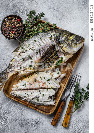 Cut baked sea bream dorado fish in a wooden tray. White background. Top view 89813415