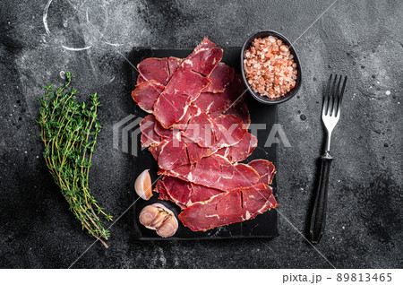 Sliced Pastrami roasted beef meat with herbs. Black background. Top view Sliced Pastrami roasted beef meat with herbs. Black background. Top view 89813465