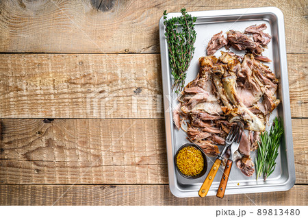 Baked pork knuckle eisbein meat on a baking pan with herbs. Wooden background. Top view. Copy space Baked pork knuckle eisbein meat on a baking pan with herbs. Wooden background. Top view. Copy space 89813480