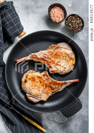 Fried tomahawk pork chop meat steak in a pan. White background. Top view 89813677