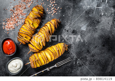 Roasted Tornado or twisted potatoes with ketchup sauce. Black background. Top view. Copy space 89814119