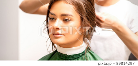 Hairstyling bride. A female hairdresser makes styling hair for the beautiful young caucasian woman in a beauty salon 89814297