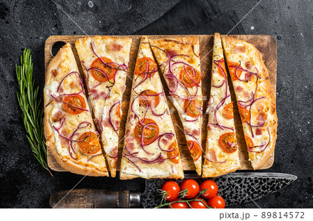 Homemade Flammkuchen or tarte flambee with cream cheese, bacon, tomato and onions. Black background. Top view Homemade Flammkuchen or tarte flambee with cream cheese, bacon, tomato and onions. Black background. Top view 89814572