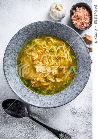 Chicken bouillon soup with leek, carrots, noodles, spring onions and parsley. White background. Top view Chicken bouillon soup with leek, carrots, noodles, spring onions and parsley. White background. Top view 89814593