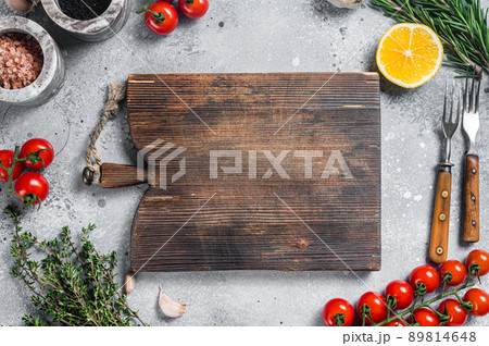 Food cooking and healthy eating background with wooden cutting board and fresh seasoning, herbs and vegetables. Gray background. Top view. Copy space 89814648