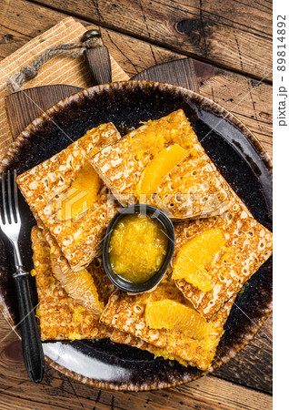 Traditional French crepe Suzette with orange sauce on a plate. Wooden background. Top view Traditional French crepe Suzette with orange sauce on a plate. Wooden background. Top view 89814892